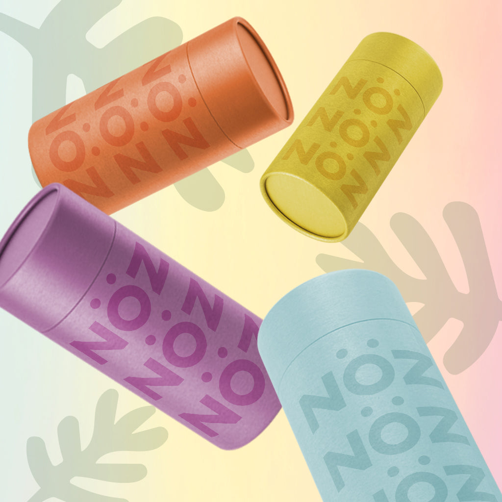 Noz reef safe, colorful, and eco sunscreen tubes in a variety of colors tossed around. Blue, yellow, orange, and purple Nozscreen.