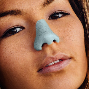 Close up of female wearing blue Noz reef safe, eco friendly sunscreen on her nose. 